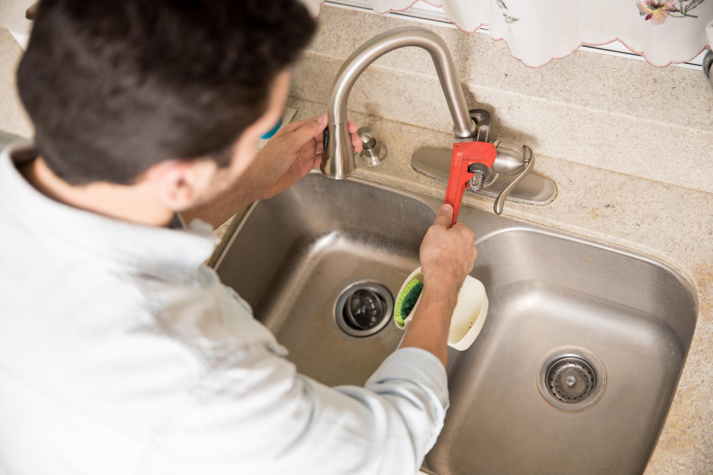 Plumber using a wrench to repair a kitchen tap and fittings